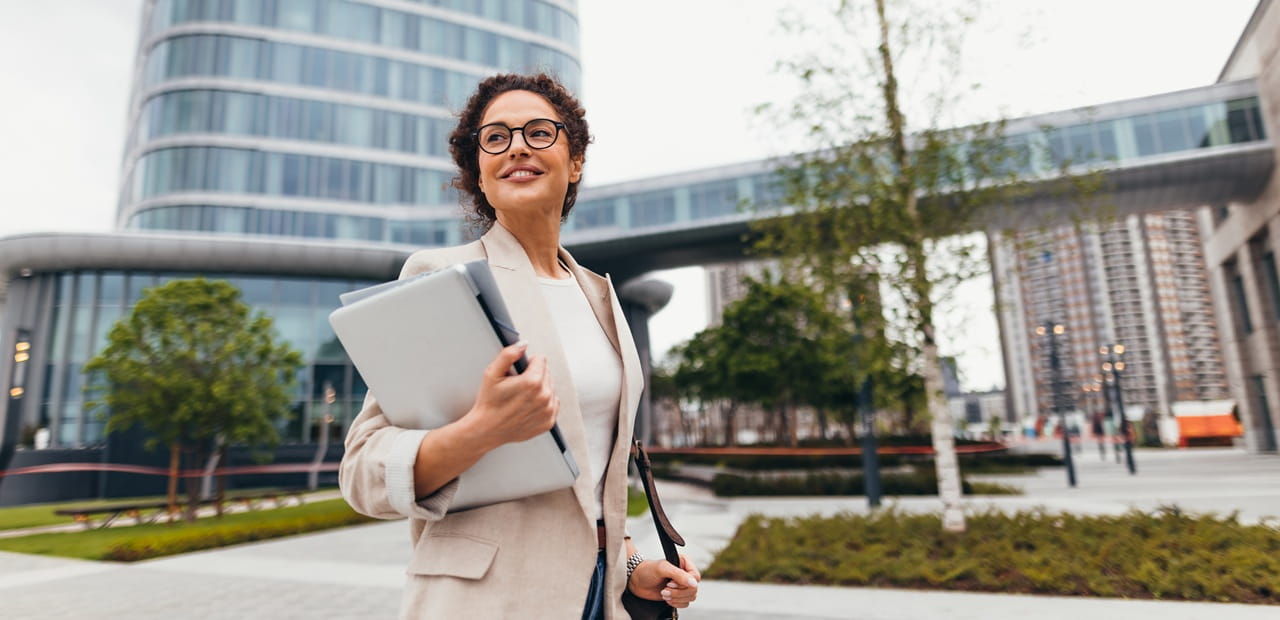 Business owner walking through a modern city with a laptop, representing how a strong digital presence supports business success.