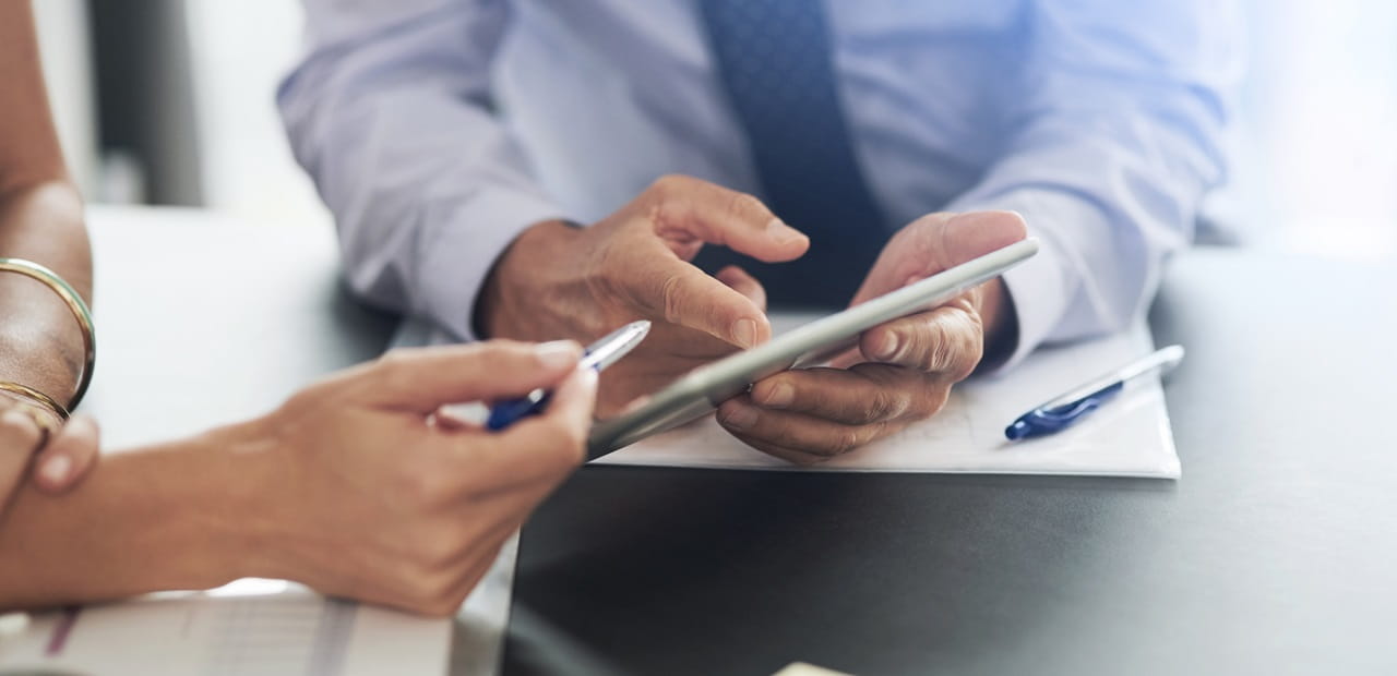 Close-up of two people's hands reviewing documents.