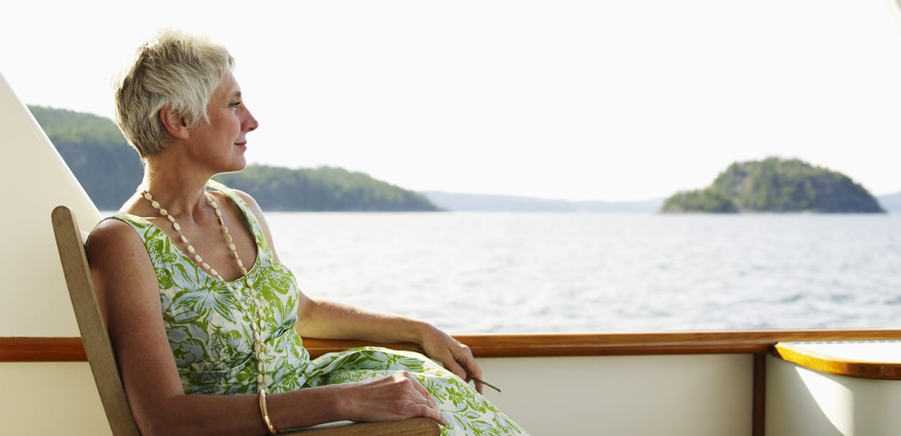Woman relaxing on a boat overlooking open water, representing preparing for a long, comfortable, and fulfilling retirement through thoughtful planning.