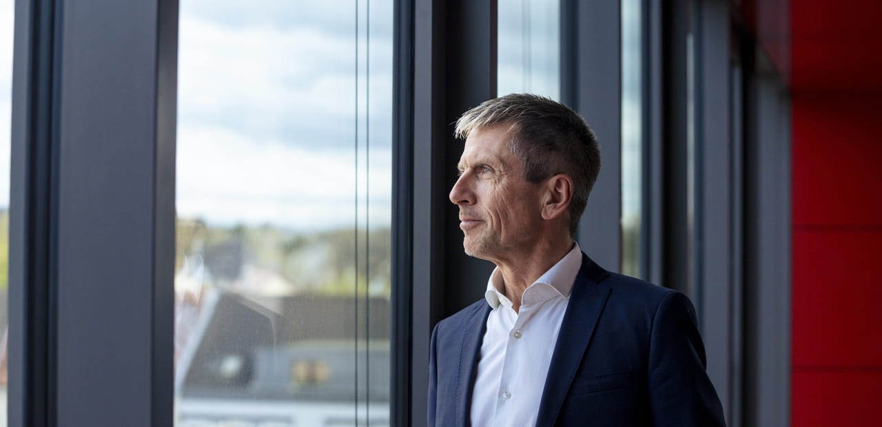 Corporate executive looking out an office window, reflecting on retirement planning and long-term financial strategy.