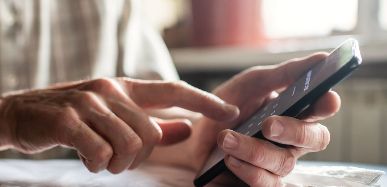 Person using a smartphone while seated at a table.