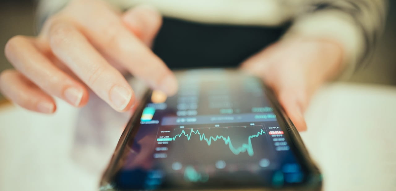 Hand using a smartphone displaying a line graph
